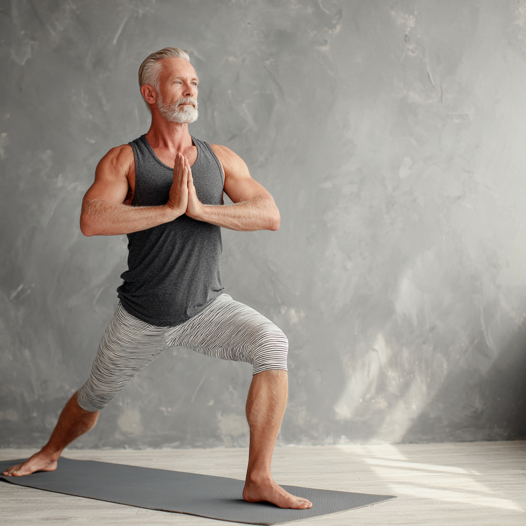 Чоловік 58 років у спортивному одязі демонструє базову позу йоги для початківців